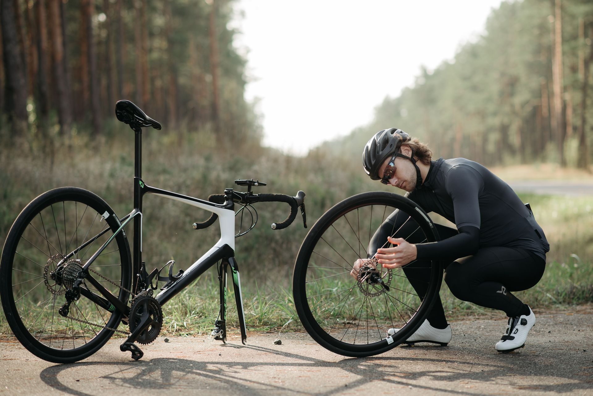 Cycliste réglant sa roue au bord d'un chemin forestier